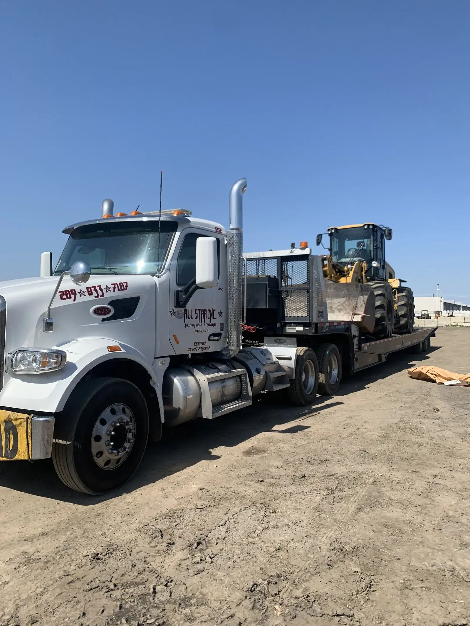Heavy equipment loaded onto an All Star heavy-haul trailer for transport.