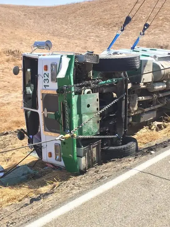 Heavy wrecker winching a rolled-over commercial truck back upright.